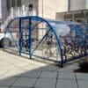 20 space original enclosure with blue metal framing and mesh door installed outside a residence with bikes parked
