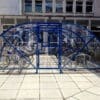 front view of the 20 space original enclosure with blue metal framing and mesh door installed outside a residence with bikes parked