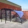 20 Space Original Enclosure with black powder-coated steel frameworks stored outside next to a brick building, with several bikes being stored