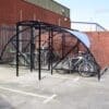 20 Space Original Enclosure with black powder-coated steel frameworks stored outside next to a brick building, with several bikes being stored
