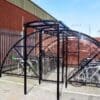 20 Space Original Enclosure with black powder-coated steel frameworks stored outside next to a brick building, with several bikes being stored