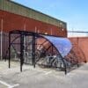 20 Space Original Enclosure with black powder-coated steel frameworks stored outside next to a brick building, with several bikes being stored