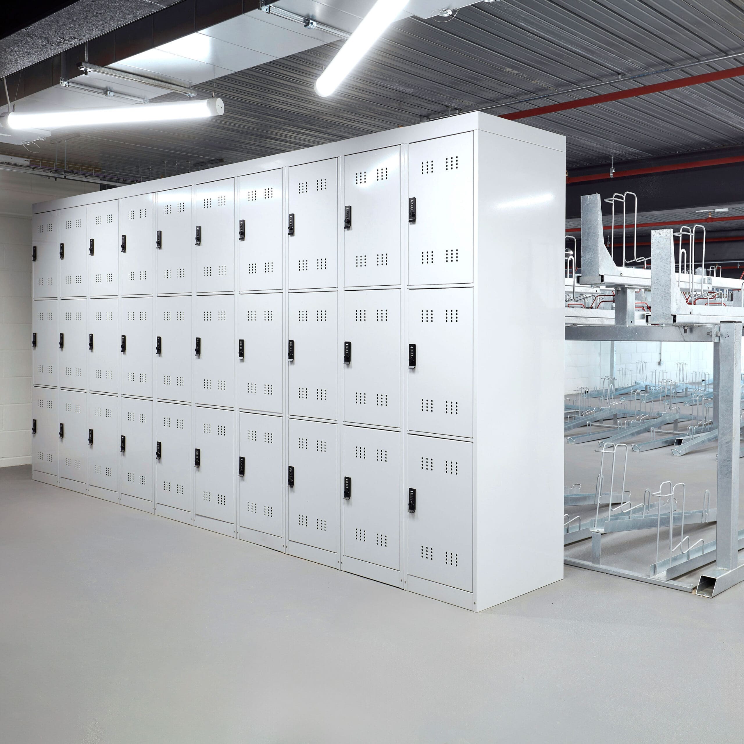 3-Tier Folding Bike Locker installed in an internal cycle storage facility with Two Tier Racks behind it