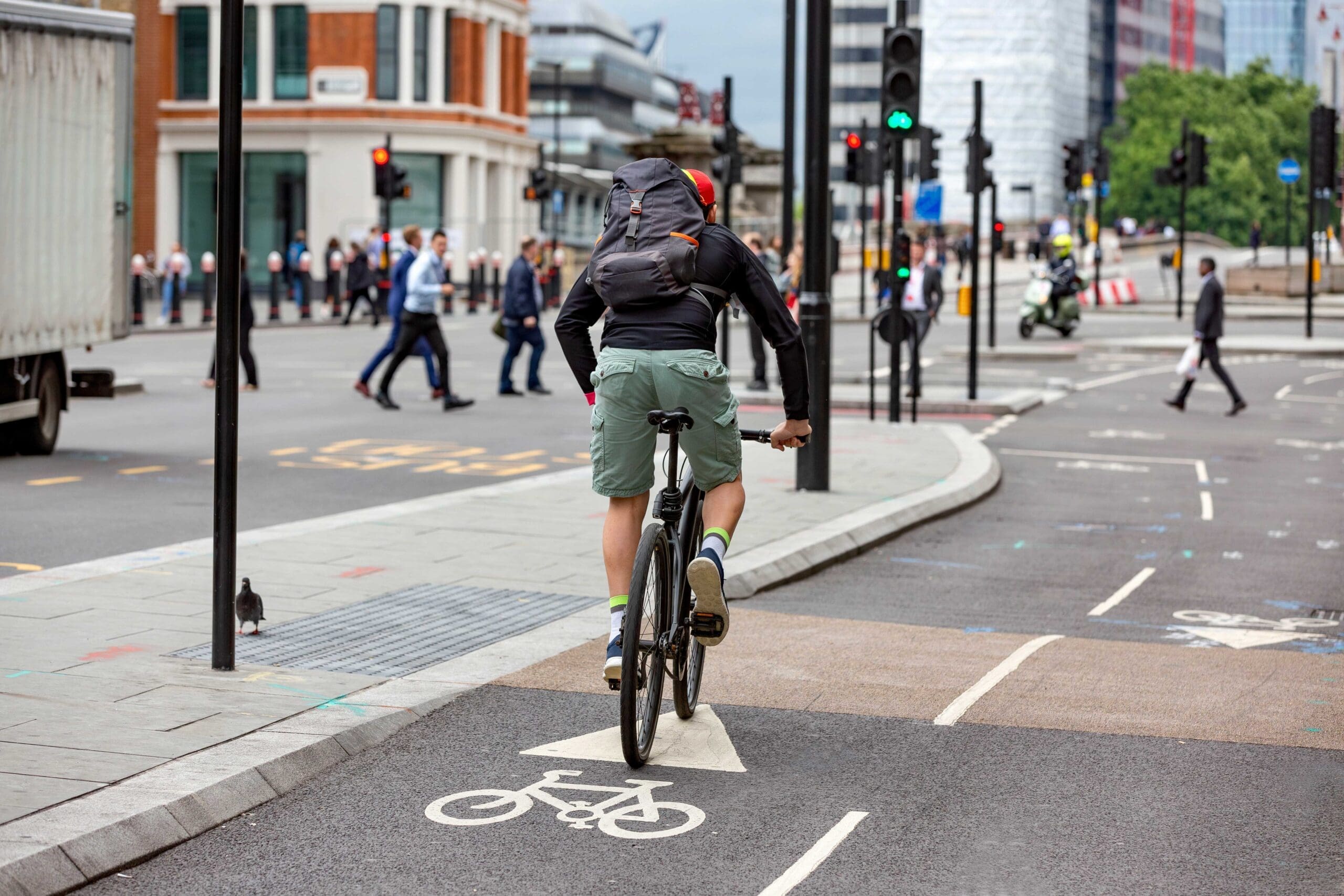 Person with a bike cycling down a busy road in London with a backpack on