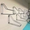 Vertical Bike Rack installed on a white brick wall in an underground bike storage facility, with two bikes on the right side being hung vertically
