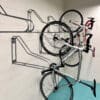 Vertical Bike Rack installed on a white brick wall in an underground bike storage facility, with two bikes on the right side being hung vertically
