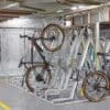 Semi Vertical Bike Rack installed in an underground cycle storage facility next to Perforated Mesh Fencing and two bikes being stored