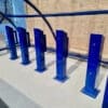 A row of blue e-bike charging stands installed outside under a blue polycarbonate bike shelter