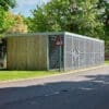 a large wooden cycle shelter with metal fencing on a lawn