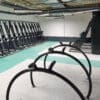 A row of jet-black powder coated Equilibrium Cycle Stands installed in an underground cycle shelter with semi vertical bike racks installed in the background