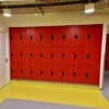 Islington Locker installed in a cycle storage end of trip facility, with red doors and black locks, on top of a yellow floor.