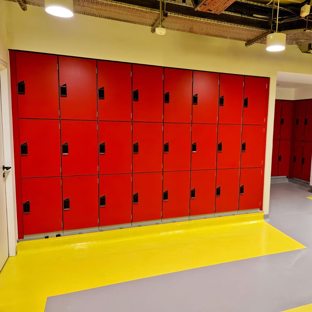 Islington Locker installed in a cycle storage end of trip facility, with red doors and black locks, on top of a yellow floor.