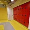 Islington Locker installed in a cycle storage end of trip facility, with red doors and black locks, on top of a yellow floor.