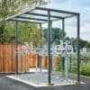 A modern outdoor bicycle parking shelter equipped with secured bike racks and surrounded by greenery and a wooden fence.
