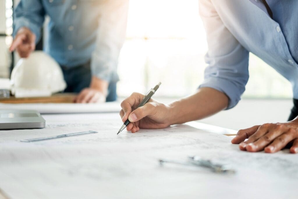Close-up Of Person's engineer Hand Drawing Plan On Blue Print with architect equipment, Architects discussing at the table, team work and work flow construction concept.