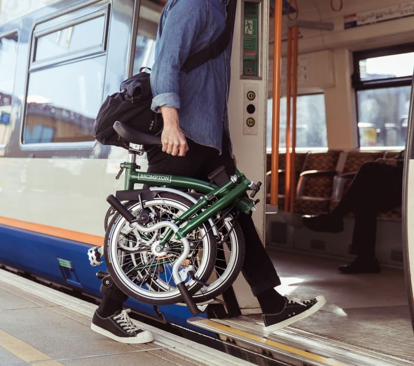 man getting onboard the train carrying a brompton folding bike