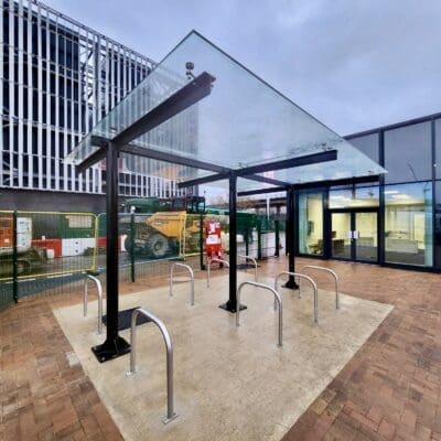 a glass roof bike rack with metal bars in front of a building