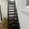 Bike Stair Ramp installed on a set of black metal stairs outside a residential property