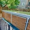 Wooden clad bike shelter with sedum roofing installed outside of a residential property with swing gates
