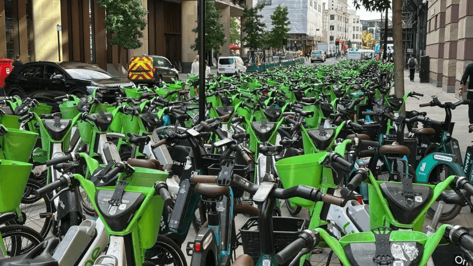Several lime bikes parked on a busy london street