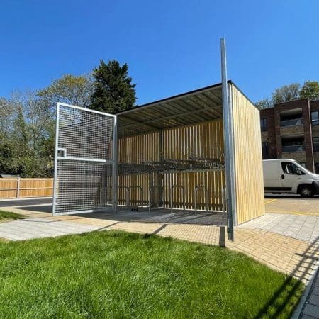 wooden bike shelter with swing mesh gate outside
