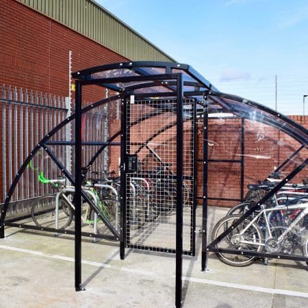 20 Space Original Enclosure with black powder-coated steel frameworks stored outside next to a brick building, with several bikes being stored