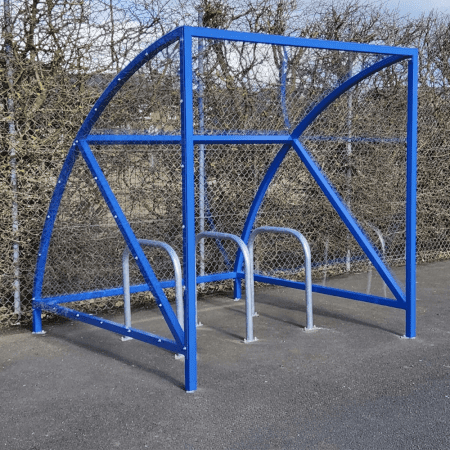 ral blue original cycle shelter with 3 sheffield stands outside in front of fence