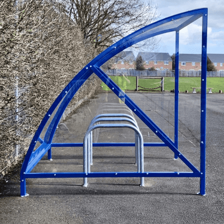 ral blue original cycle shelter with 3 sheffield stands outside in front of fence