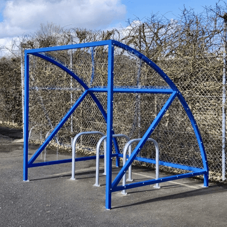 ral blue original cycle shelter with 3 sheffield stands outside in front of fence