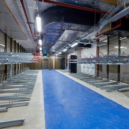 Two Tier Gas Assisted Bike Racks installed in an underground cycle storage facility next to a cycle locker
