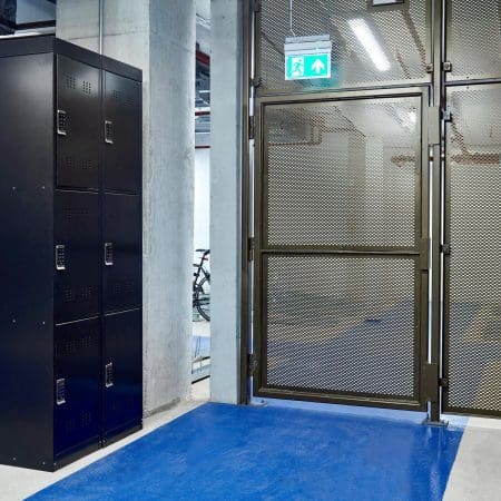 Perforated mesh fencing swing gate installed in an underground cycle storage facility next to a 3 tier bike locker