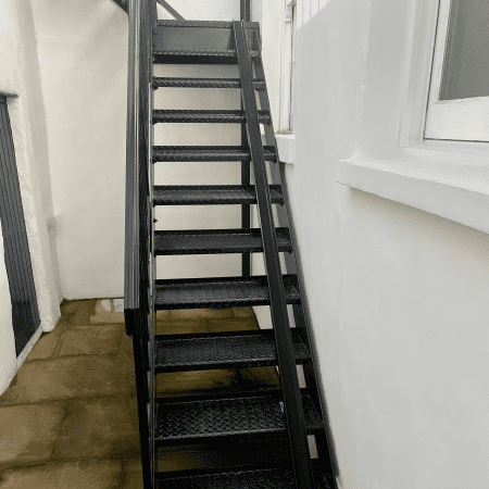 Bike Stair Ramp installed on a set of black metal stairs outside a residential property