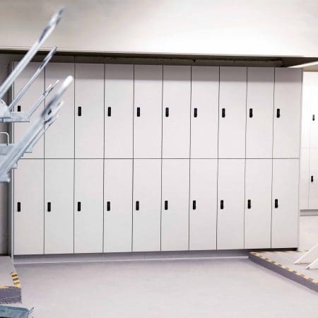 Row of white Camden Lockers installed in an underground cycle storage facility, with Two Tier Rack handles on the left side of the room