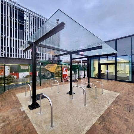 a glass roof bike rack with metal bars in front of a building