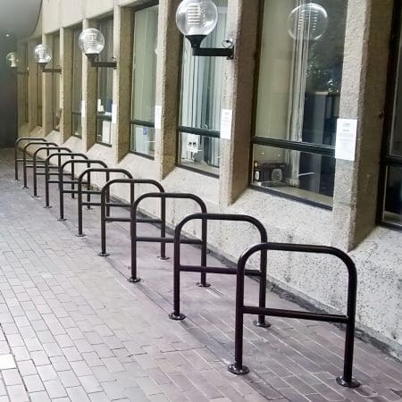 The Crossbar Cycle Stands in a row installed outside a school building, in galvanised RAL colour black