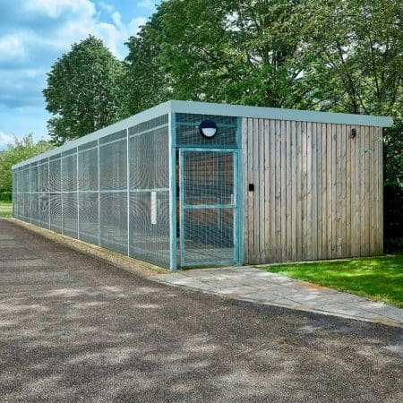 a large wooden cycle shelter with metal fencing and swing gate entry