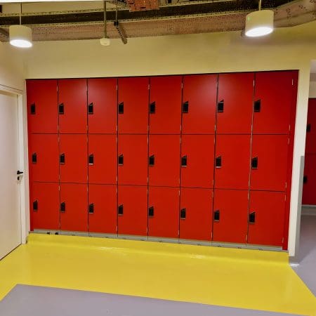 Islington Locker installed in a cycle storage end of trip facility, with red doors and black locks, on top of a yellow floor.