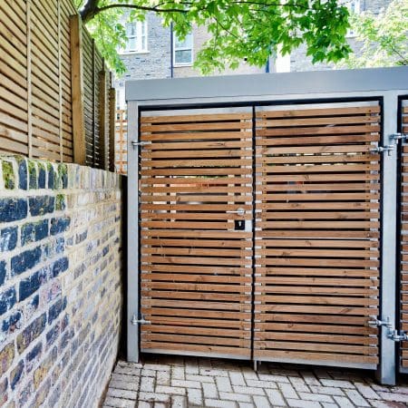 wooden bicycle shelter and bin storage facility outside under a tree