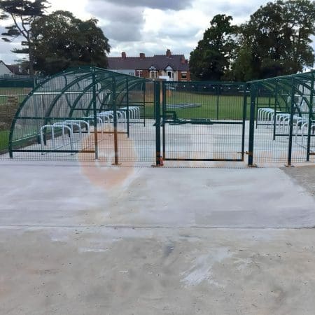 Black and metal bike shelter with clear cresent roof and paladin mesh fencing installed around