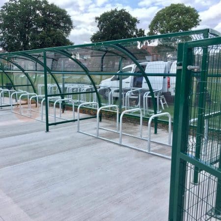 Black and metal bike shelter with clear cresent roof and galvanised steel bike racks