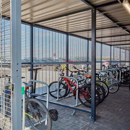 a group of bicycles parked in a covered metal bike storage facility