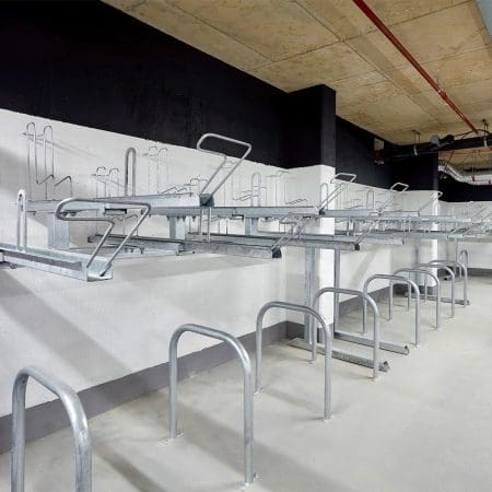 row of Two Tier Cycle Racks inside of a commercial building with sheffield stands underneath