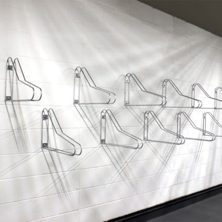 Vertical Bike Rack installed in an underground storage facility anchored on a white brick wall