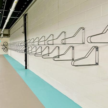 Vertical Bike Rack installed on a white brick wall in an underground bike storage facility with a bike hanging securely in the distance