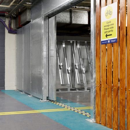 Perforated Mesh Fencing installed in an underground cycling storage facility with a sign showing the cycle storage and timber slat fencing