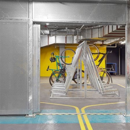 Semi Vertical Bike Rack installed in an underground cycle storage facility behind Perforated Mesh Security Fencing and bike being stored semi-vertically